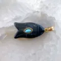 Vue rapprochée du pendentif poisson en pierre noire avec turquoise et anneau doré. - Obsidienne