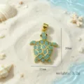 Vue détaillée du pendentif tortue plaqué or avec incrustation turquoise, fond de plage. - Pendentif Tortue / Or