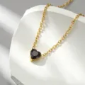 Primo piano dettagliato del ciondolo a forma di cuore nero su una catena di collana dorata fine. - Strass a cuore nero - x1316
