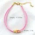 Vista dettagliata del bracciale in corda intrecciata multistrato rosa con perle dorate. - 01# (Rosa)