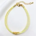 Vista dettagliata del bracciale in corda intrecciata gialla a più strati con perle dorate. - 18# (Giallo)