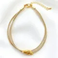 Dettaglio in primo piano del bracciale in filo d'oro multistrand con ciondolo centrale lucido. - 10# (Oro)