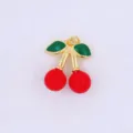 Close-up detail view of a 3D red cherry charm with green enamel leaves and gold trim. - Style F