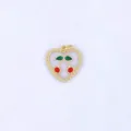 Close up of a sweet heart shaped cherry pendant with enamel red and green details and gold bead trim. - Style G