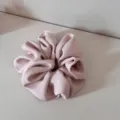 Detailed shot of a stylish pink fabric hair scrunchie, soft texture and chic pleated design. - Pink