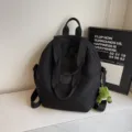 Black casual large capacity backpack with top handles and cute green dinosaur plush pendant. - With Dragon Pendant / Black