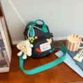 Small black canvas crossbody bag with colorful hearts, green strap and cute plush ghost pendant. - Black + Cheese Pendant