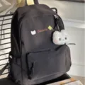 Close-up of black cute school backpack with cat embroidery and fluffy plush pendant detail. - Black with Cat