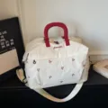 Expandable travel duffel bag in cream white with red handles and bow embroidery for trips. - Off White