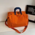 Expandable orange travel duffel bag with blue handles, large capacity for short trips. - Orange