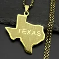 Detail shot of a gold-colored Texas map pendant necklace featuring star patterns and engraved text. - Gold