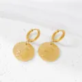 Close-up detail of textured gold round coin pendant hoop earrings, minimalist stainless steel. - Gold