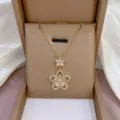 Nahaufnahme einer zarten vergoldeten doppelten Blumen Zirkonia Halskette im Etui. - X0950 Gold Doppelte Blume