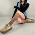 Brown knit over-the-knee leg warmers paired with retro casual sneakers for autumn winter look. - Brown