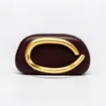 Burgundy hard-shell evening clutch bag featuring a striking sculptural gold metal handle. - Leather Burgundy