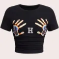 Nahaufnahme des schwarzen T-Shirts mit Strass-Buchstabe H und auffälligem Hand-Print. - S / Stil H