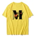 Close-up detail of the vintage floral letter M print on a vibrant yellow women's t-shirt. - S / Tops / Letter M