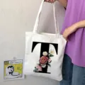 Primo piano dettagliato della borsa tote in tela bianca con lettera T e stampa di fiori. - Lettera T / 15x13