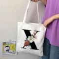 Primo piano dettaglio della borsa di tela bianca con lettera X nera e stampa floreale. - Lettera X / 15x13