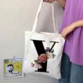 Primo piano della borsa tote in tela bianca con una grande lettera Y nera audace e stampa floreale. - Lettera Y / 15x13
