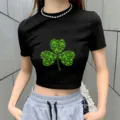 Close-up detail view of women's black short-sleeve crop top featuring green shamrock clover graphic print. - S / Black