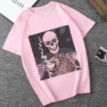 Pink short sleeve t-shirt featuring a unique graphic of a skeleton drinking coffee with a cat. - Pink (21058)