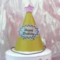 Close-up detail of the sparkling gold glitter birthday party hat featuring pink star. - Glitter Gold