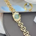 Detailaufnahme der goldenen Kettenglieder-Uhr mit quadratischem grünem Zifferblatt und Ziffern. - Goldgehäuse/Grünes Zifferblatt