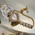 Nahaufnahme einer modischen herzförmigen Strass-Quarzuhr mit doppeltem Perlenarmband. - Goldene Uhr mit Ziffernblatt