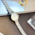 Nahaufnahme einer eleganten Damen-Quarzarmbanduhr mit metallischem Nietengeflechtarmband. - Zweifarbig (Gold & Silber)