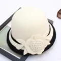 Close-up detail of the elegant wool felt cloche hat featuring 3D floral accent and black brim. - M (56-58cm) / Wrapped Rose – Milky White