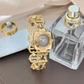 Detailaufnahme einer goldenen Damen-Quarzuhr mit quadratischem Zifferblatt und Kettenglieder. - Gold/Schwarzes Zifferblatt