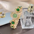 Detailed shot of luxury gold women watch with green stones and sparkling rhinestones accent. - Green