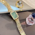 Detailaufnahme der grünen rechteckigen Strass-Quarzuhr mit goldenem Kettenarmband. - Gold Grün