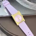 Nahaufnahme des quadratischen Quarzuhr, goldenes Gehäuse, rosa Zifferblatt, lila Silikonarmband. - Hellviolett