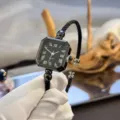 Nahaufnahme der schwarzen quadratischen Quarzuhr mit Armreif und klassischen Ziffern. - Römische Zahlen Schwarz
