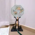 Detailed view of traditional Chinese embroidered round fan with wooden stand and green tassel. - 27