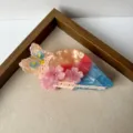 Detailed shot of a cute owl-shaped acrylic hair claw clip with pink cherry blossom decor. - Owl