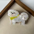 Close-up detail of cute white dog hair claw clip with yellow collar, stylish hair accessory. - White Puppy