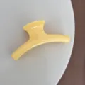 Gros plan d'une pince à cheveux jaune élégante, design simple et épuré pour le coiffage quotidien. - Cintre Style / Jaune