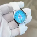 Nahaufnahme der Kinder Silikonuhr mit blauem Regenbogen Zifferblatt und weissem Silikonarmband. - Weiß