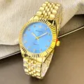 Goldene Quarzuhr Detailansicht mit klassischem hellblauem Zifferblatt und Metallarmband. - Herrenstil / Blau