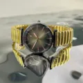 Primer plano detallado del reloj de mujer con esfera facetada y correa elástica dorada. - Dorado