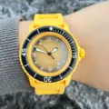 Detailansicht der gelben Silikonarmband Quarzuhr mit Zifferblatt und schwarzer Lünette. - Gelb