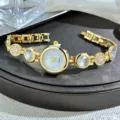 Detailaufnahme einer goldenen Quarzuhr mit glitzernden Strasssteinen und Edelsteinen. - Weiß