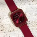 Close-up of women quartz watch featuring red silicone strap, rose gold square case and red dial. - Burgundy