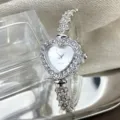 Nahaufnahme des silbernen Herz-Quarzuhrwerks mit glitzernden Strasssteinen und Blumenarmband. - Silber Weiß