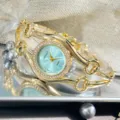 Elegante goldfarbene Quarz-Armbanduhr mit hellblauem Zifferblatt und funkelnder Lünette. - Hellblau