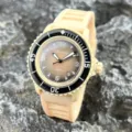 Detailansicht Quarzarmbanduhr mit beigem Silikonarmband, schwarzer Lünette und braunem Zifferblatt. - Gebrochenes Weiß