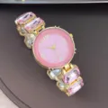 Elegante rosafarbene Kristall Quarz Armbanduhr mit rundem Zifferblatt in Goldoptik. - Rosa